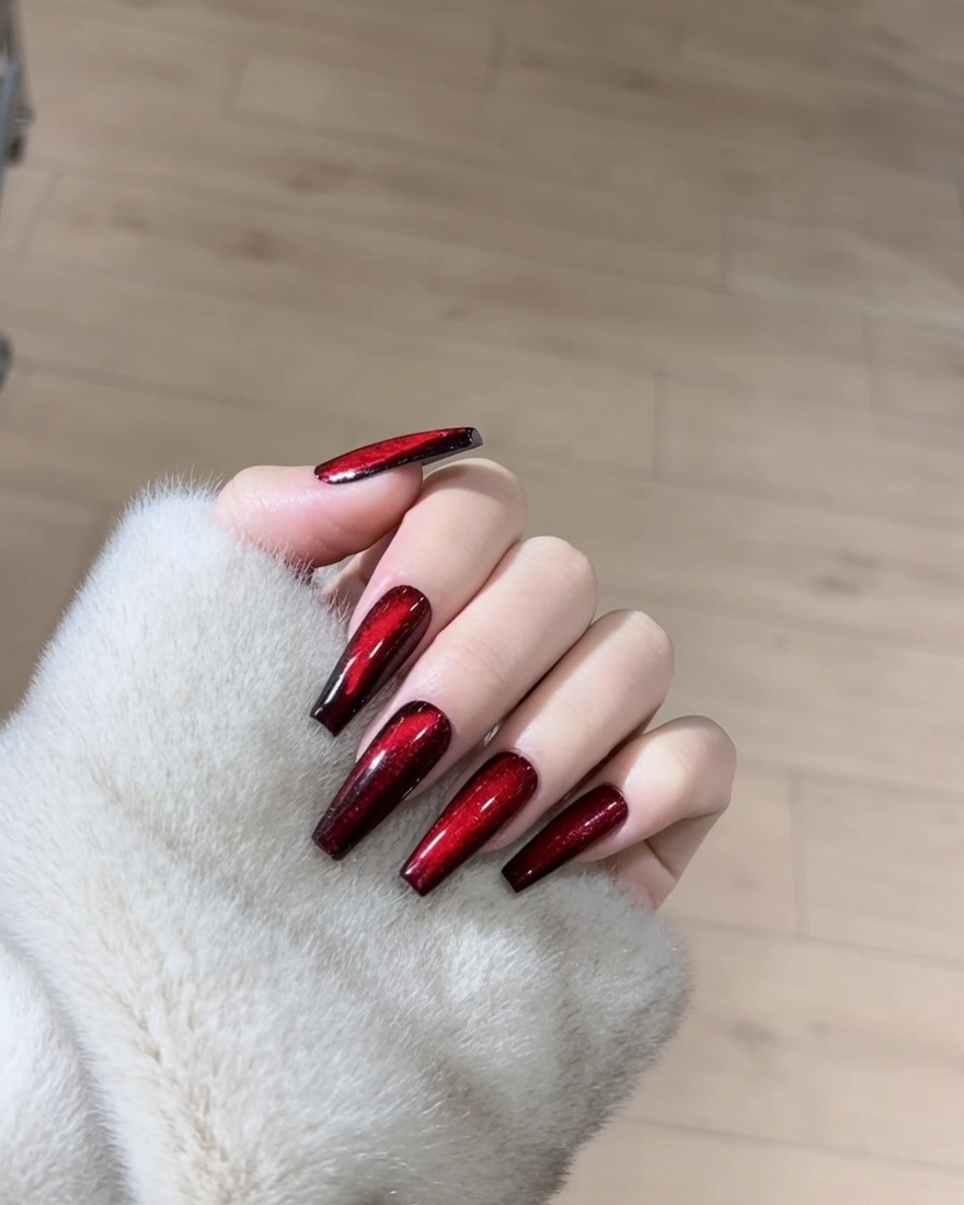 Primer plano de una uña siendo cubierta con un esmalte en gel magnético rojo brillante.