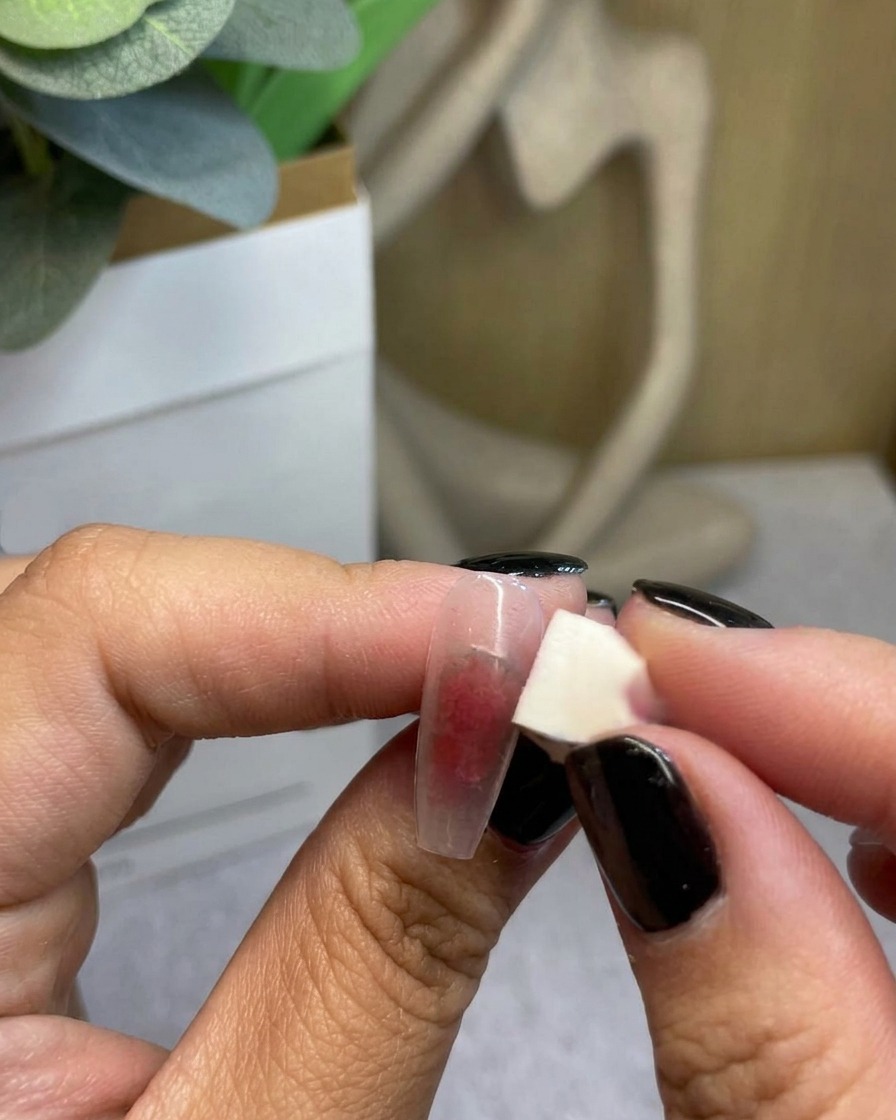 Primer plano de una esponja difuminando gel rojo hacia afuera para completar la transición del degradado.
