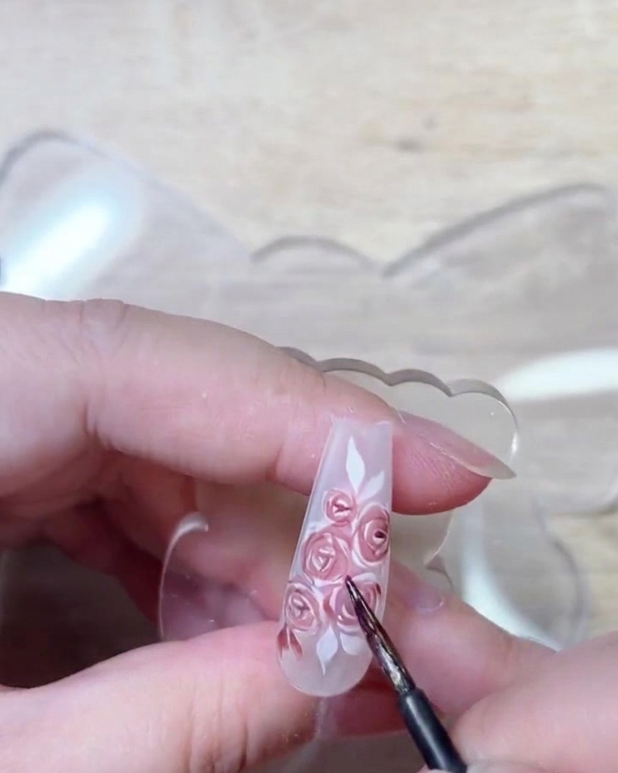 Detalle de pincel aplicando gel rojo oscuro para realzar las sombras y la estructura de los pétalos.