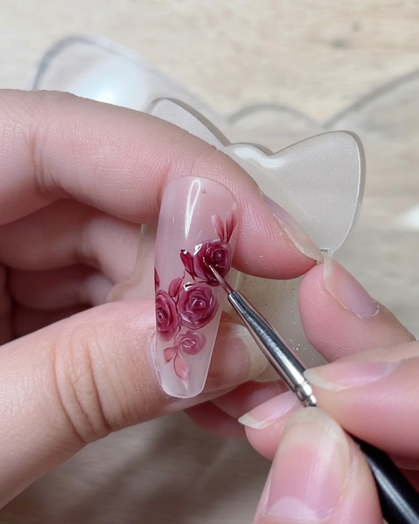 Un pincel de detalle trazando líneas rojas oscuras y nítidas para definir los pliegues de los pétalos.