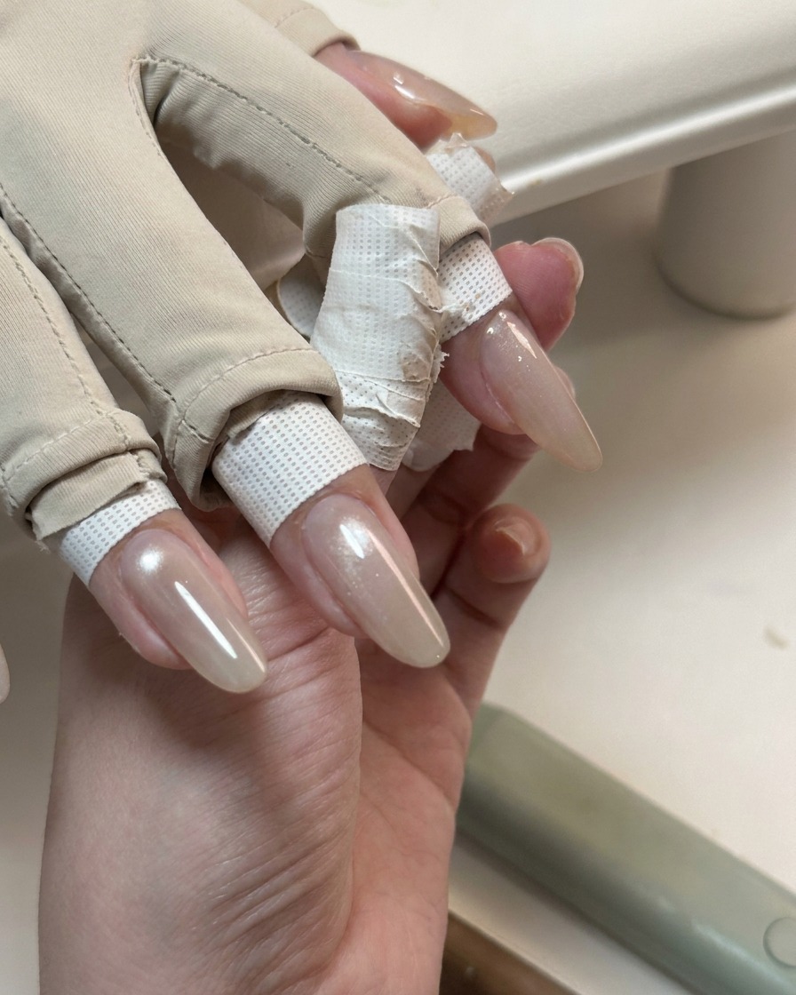 Una mano que muestra uñas largas cubiertas con una capa de gel ojo de gato brillante y traslúcido.