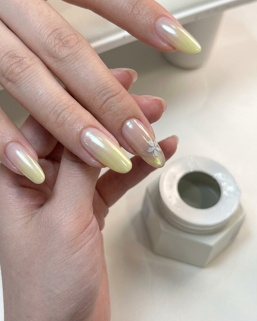 Una mano con degradado terminado y nail art floral curando bajo una lámpara UV.
