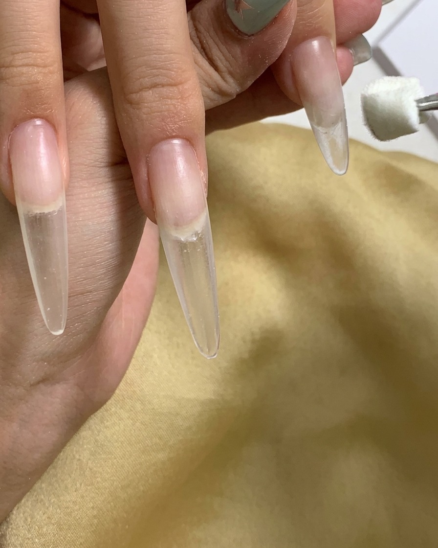 Primer plano mostrando una esponja aplicando gel en el área de la cutícula de la uña.