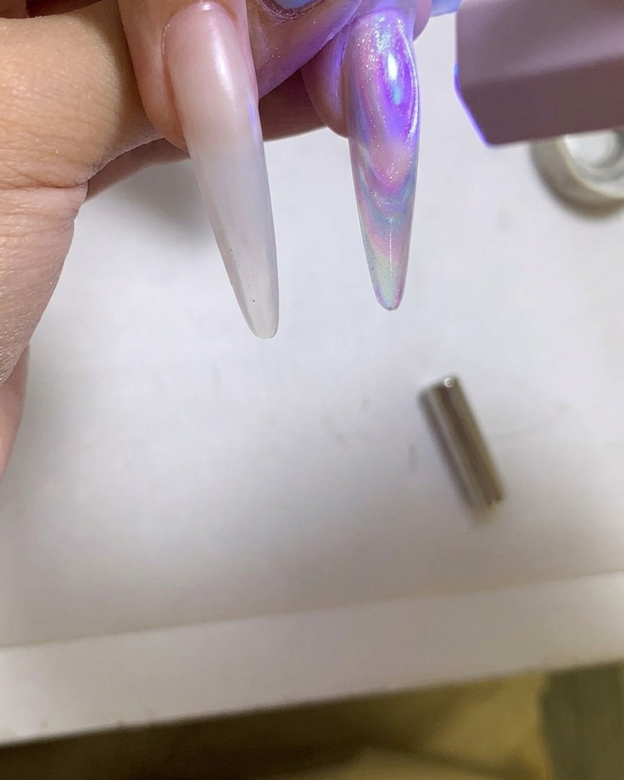 Una lámpara UV/LED portátil curando una uña de gel cat eye brillante.