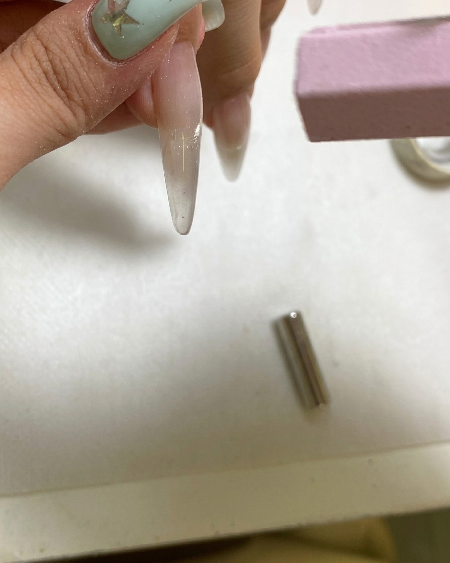 Una pequeña lámpara UV portátil curando una uña de gel recién magnetizada.