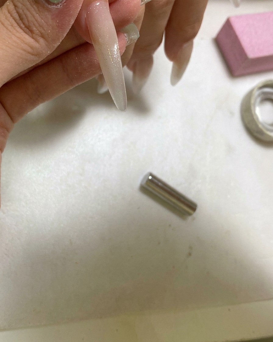 Una lámpara UV portátil curando una uña que ha sido estilizada con un efecto cat eye de bola de cristal.