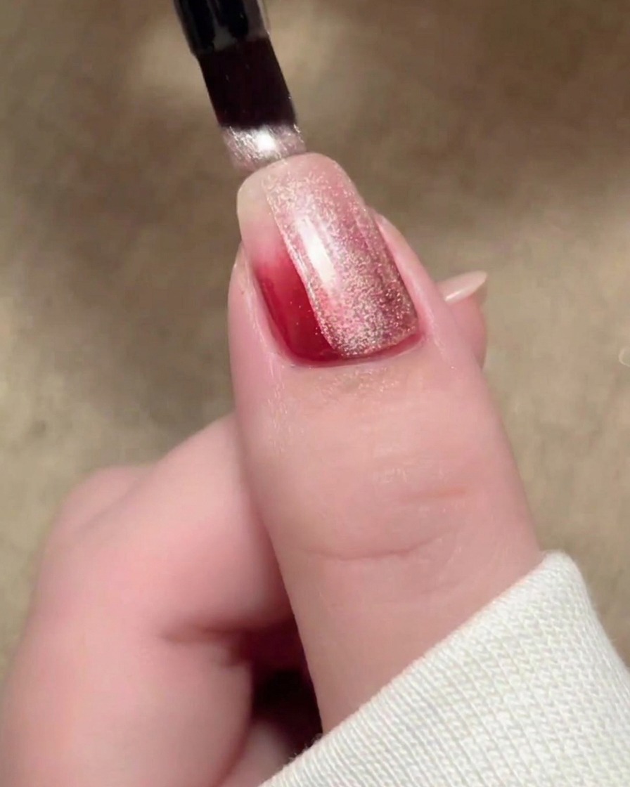 Una pincelada de esmalte magnético cat-eye beige cubriendo la superficie de la uña.