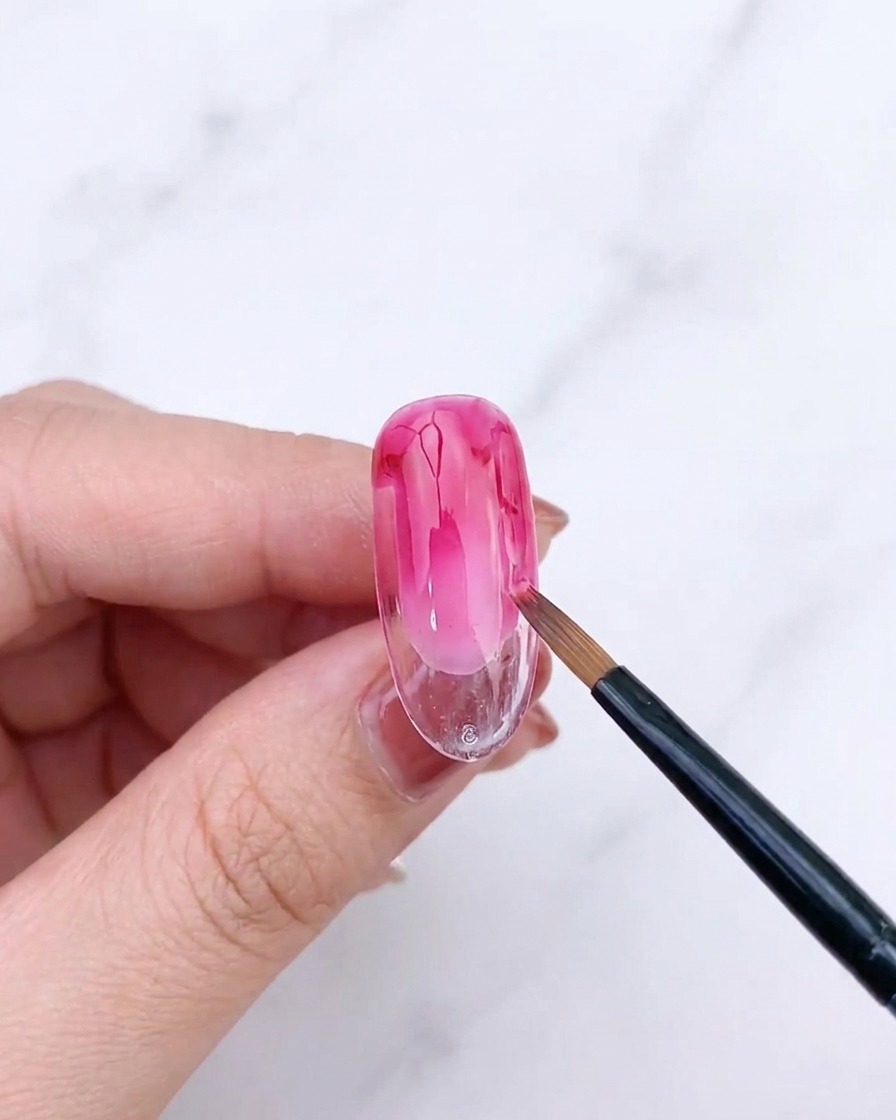 Pincel de abanico difuminando la segunda capa de gel rosa.