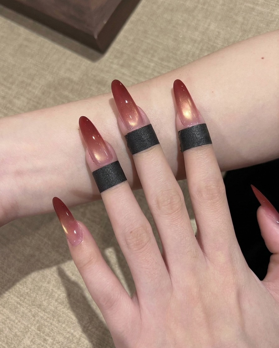 Un primer plano de un pincel de uñas aplicando esmalte de gel rojo en la punta de una uña postiza larga en forma de almendra.