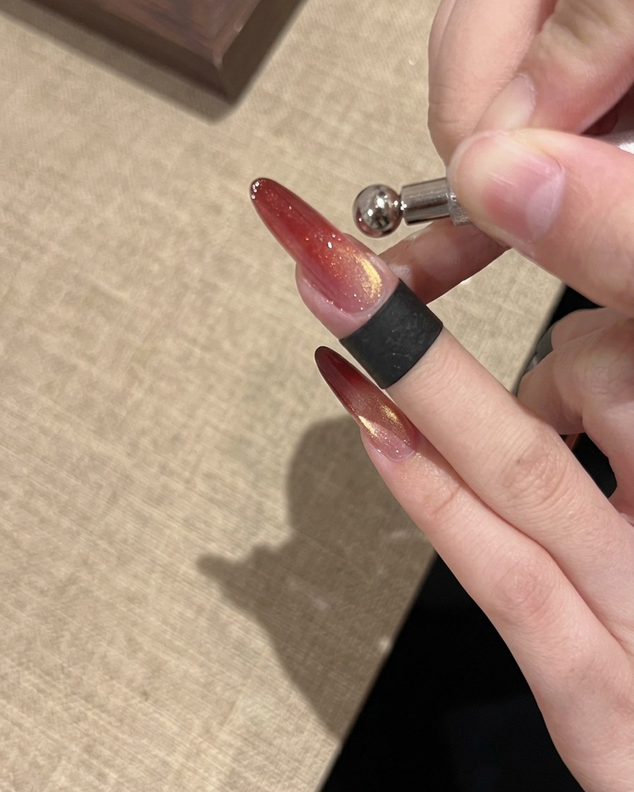 Una herramienta de imán de anillo utilizada para dar forma a un reflejo brillante y concentrado de ojo de gato en la uña.