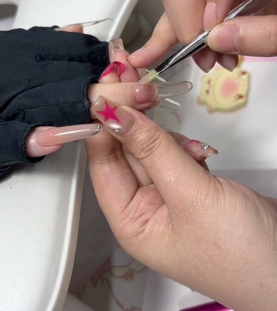 Técnica de uñas usando un pincel fino para suavizar cuidadosamente el gel cerca de la cutícula en una uña esculpida.