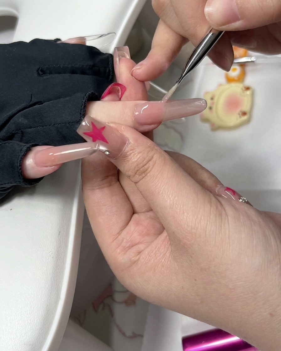 Vista en primer plano de una herramienta de precisión y una pequeña esponja limpiando el lateral de una uña preparada.