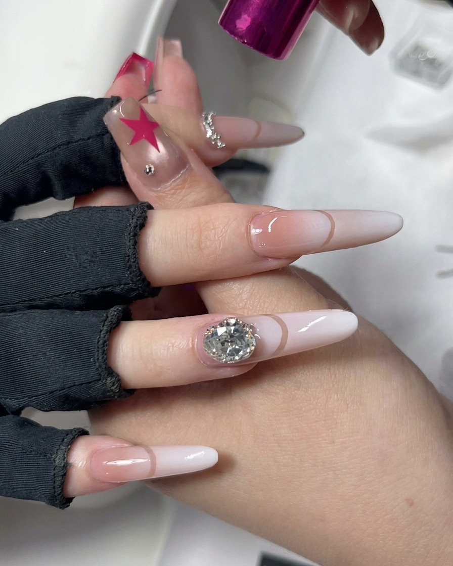 Una mano colocada bajo una lámpara rosa y compacta de curado de uñas UV/LED, mostrando un diseño de nail art decorativo.