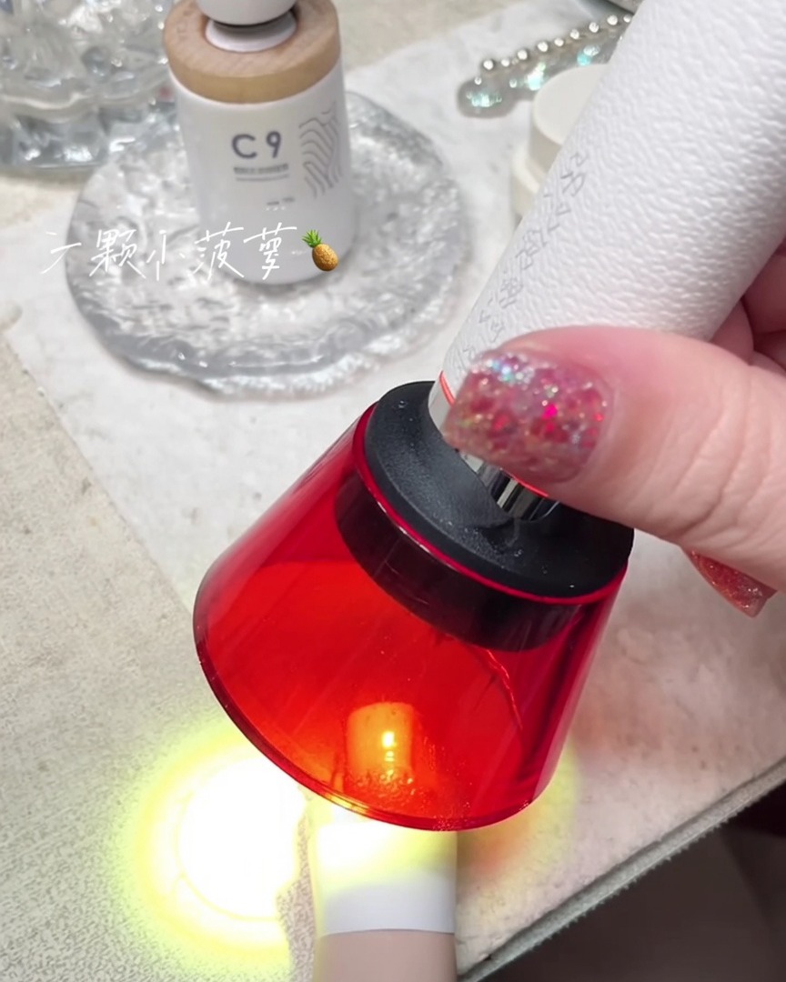 Una mini lámpara UV portátil de luz roja curando una uña.