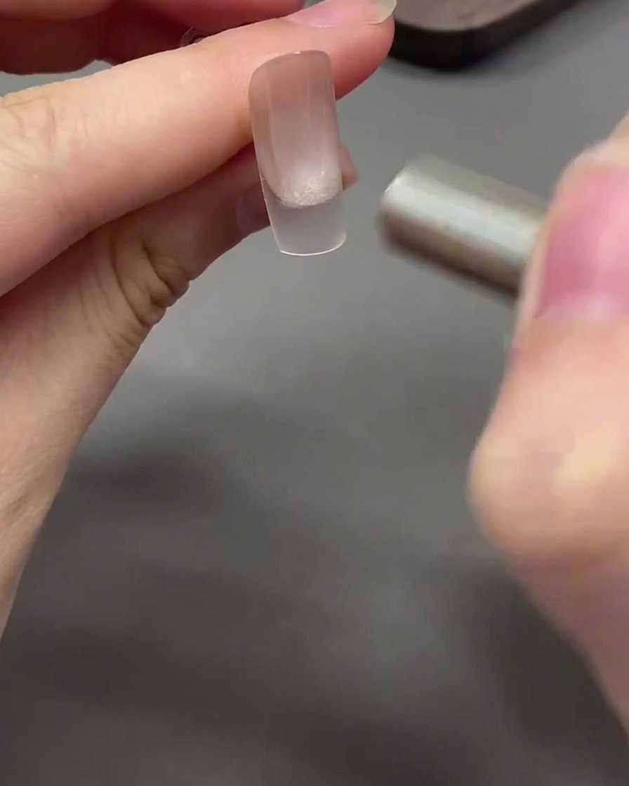 Un imán moviéndose de forma curva alrededor de la punta de la uña para dar al gel ojo de gato un efecto de cristal.