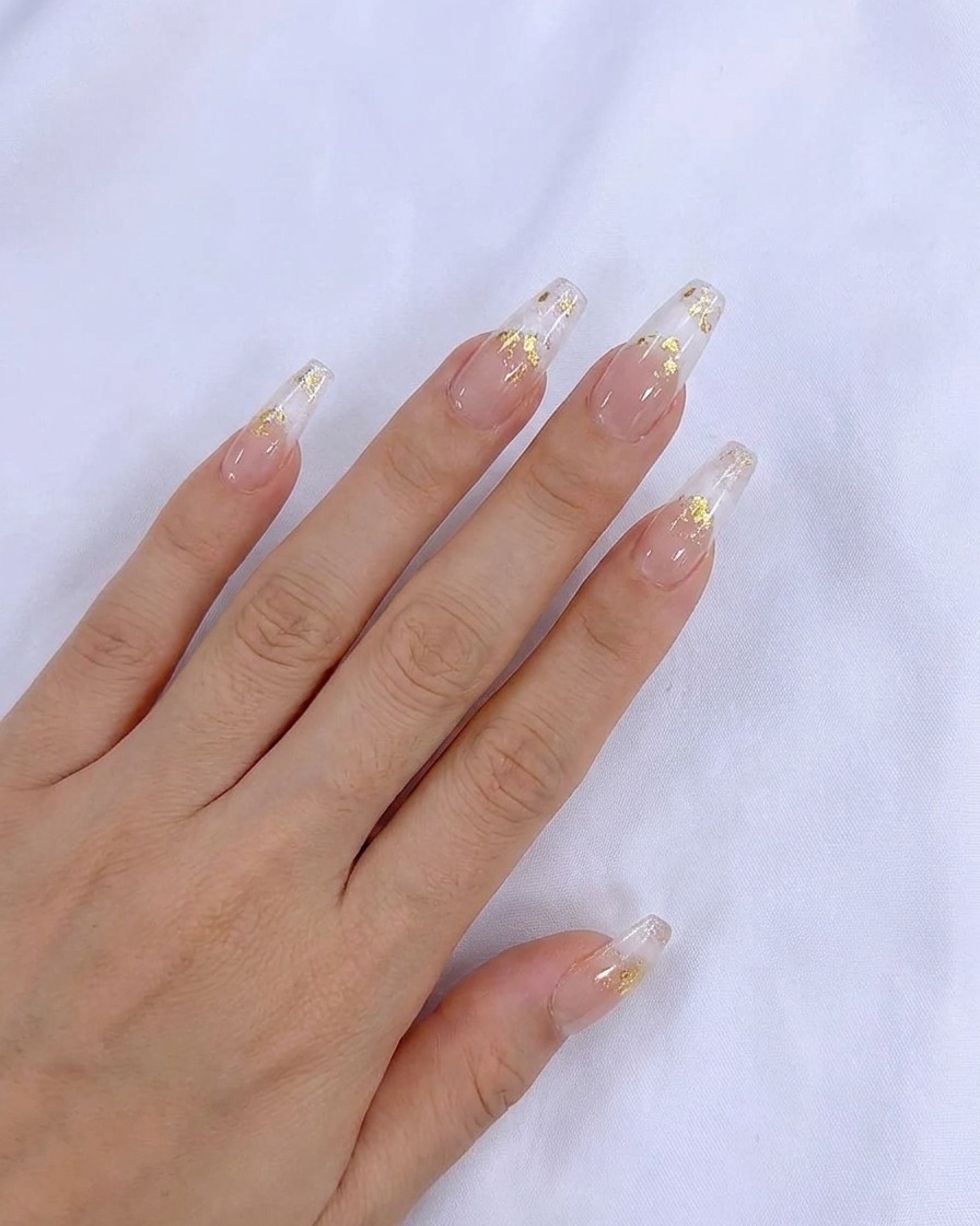 Un pincel aplicando una capa uniforme de esmalte en gel nude translúcido sobre la uña natural.