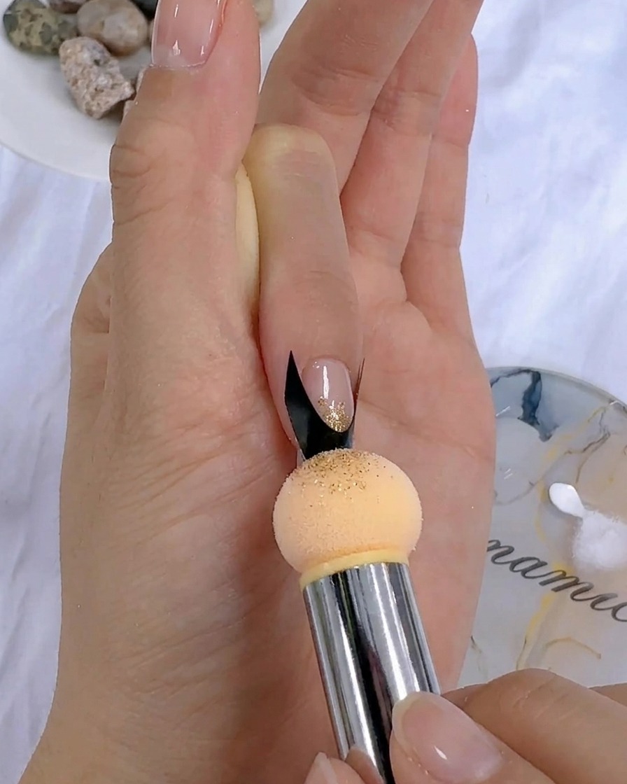 Una herramienta de esponja aplicando gel de color a toquecitos sobre una uña cerca de una pegatina francesa.
