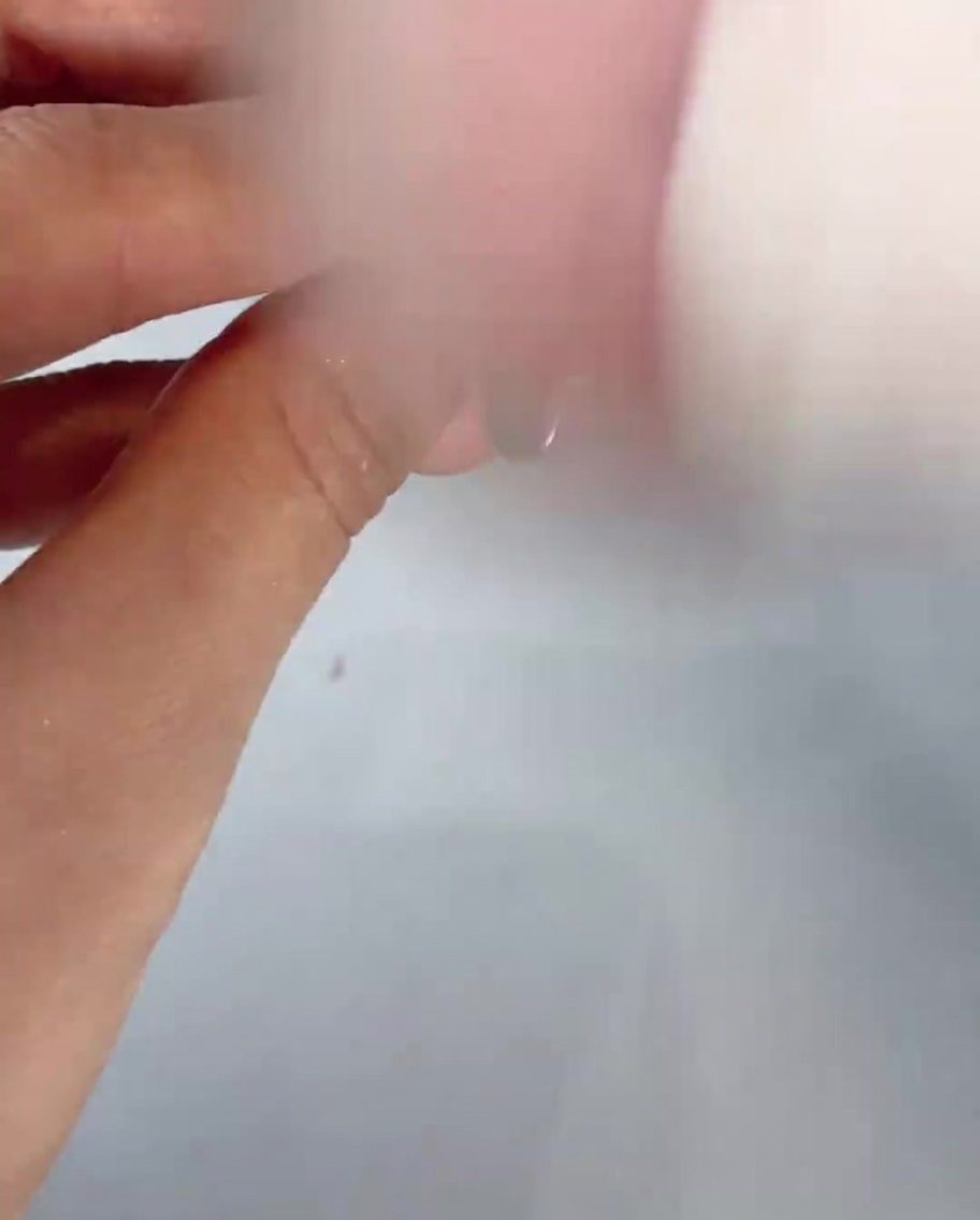 Una brocha suave y esponjosa barriendo el polvo residual de un dedo con manicura.