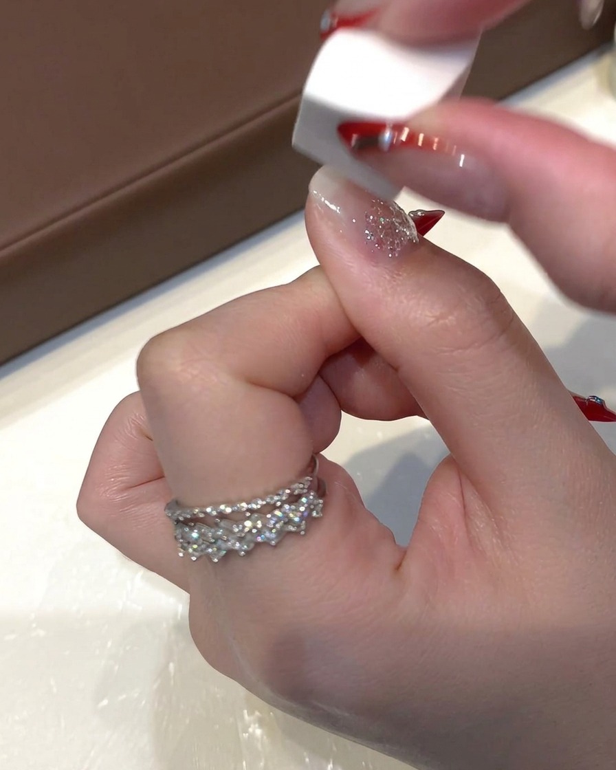 Una pequeña esponja de maquillaje blanca dando ligeras toquecitos sobre el gel de lentejuelas húmedo en la uña para aplanar el glitter.