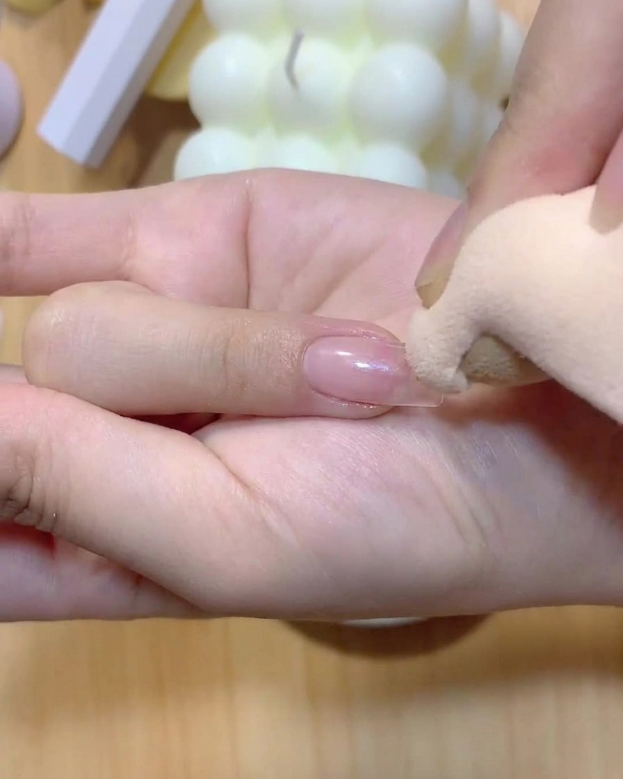 Una esponja de maquillaje aplicando color suavemente sobre una uña para crear un degradado ombré.