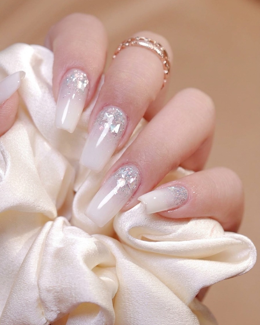 Un pincel aplicando un top coat brillante de manera uniforme sobre la superficie de una uña decorada.
