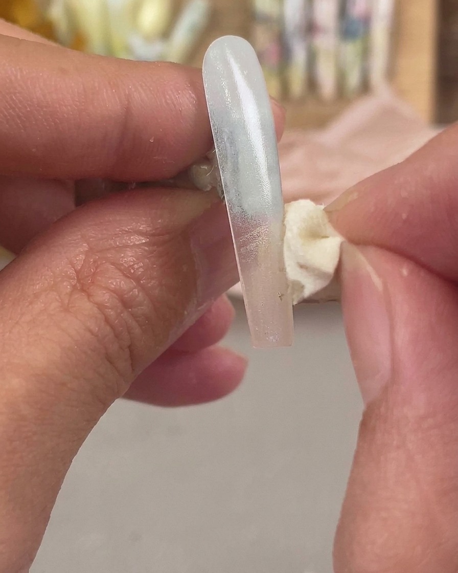 Una esponja cosmética aplicando un segundo color en la punta de la extensión de la uña para difuminar el efecto ombré.