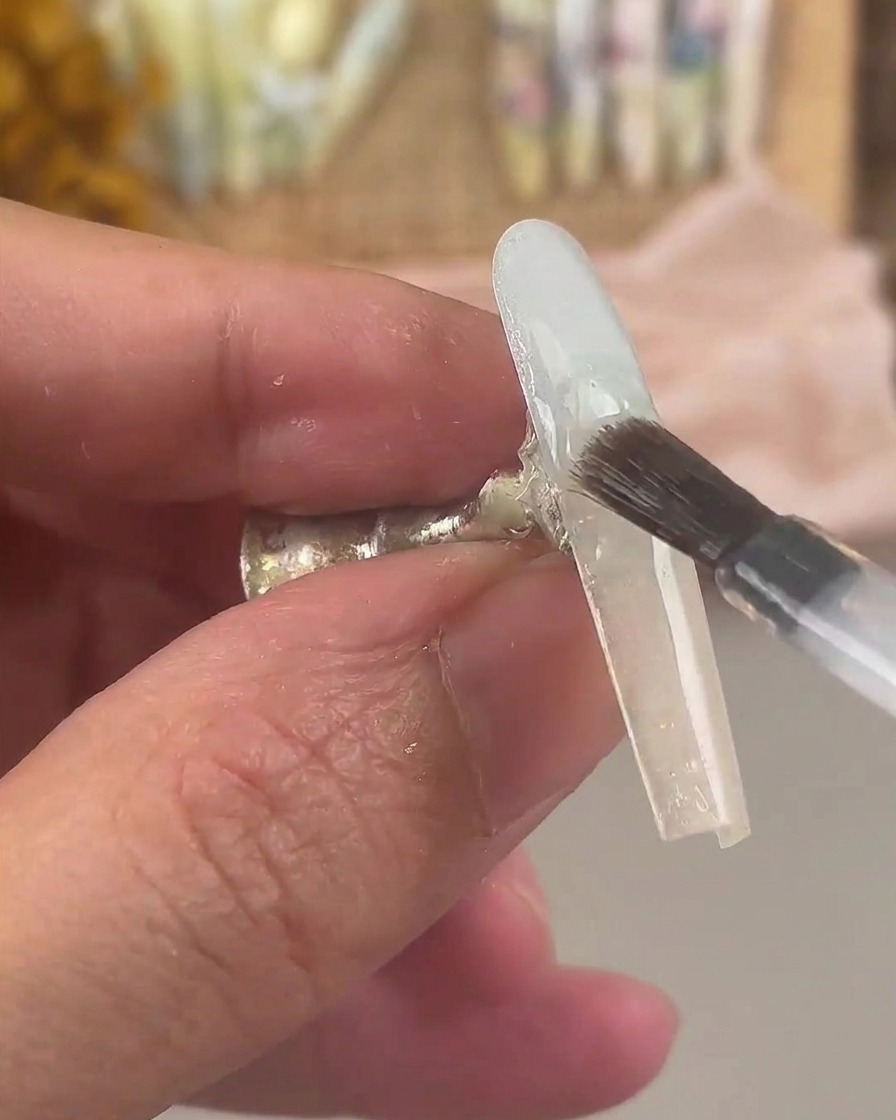 Un pincel cubriendo la uña con degradado usando una capa de gel base transparente.