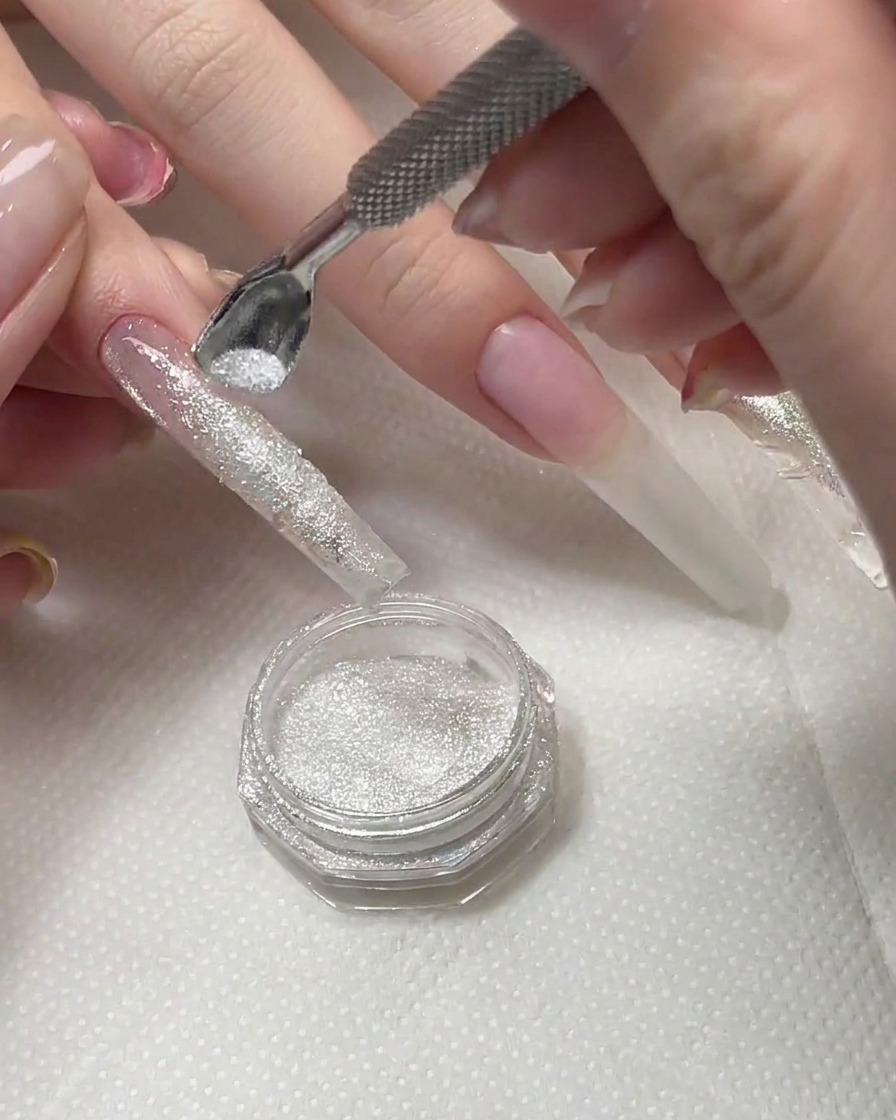 Cepillo barriendo el exceso de polvo de diamante de la superficie de una uña curada.