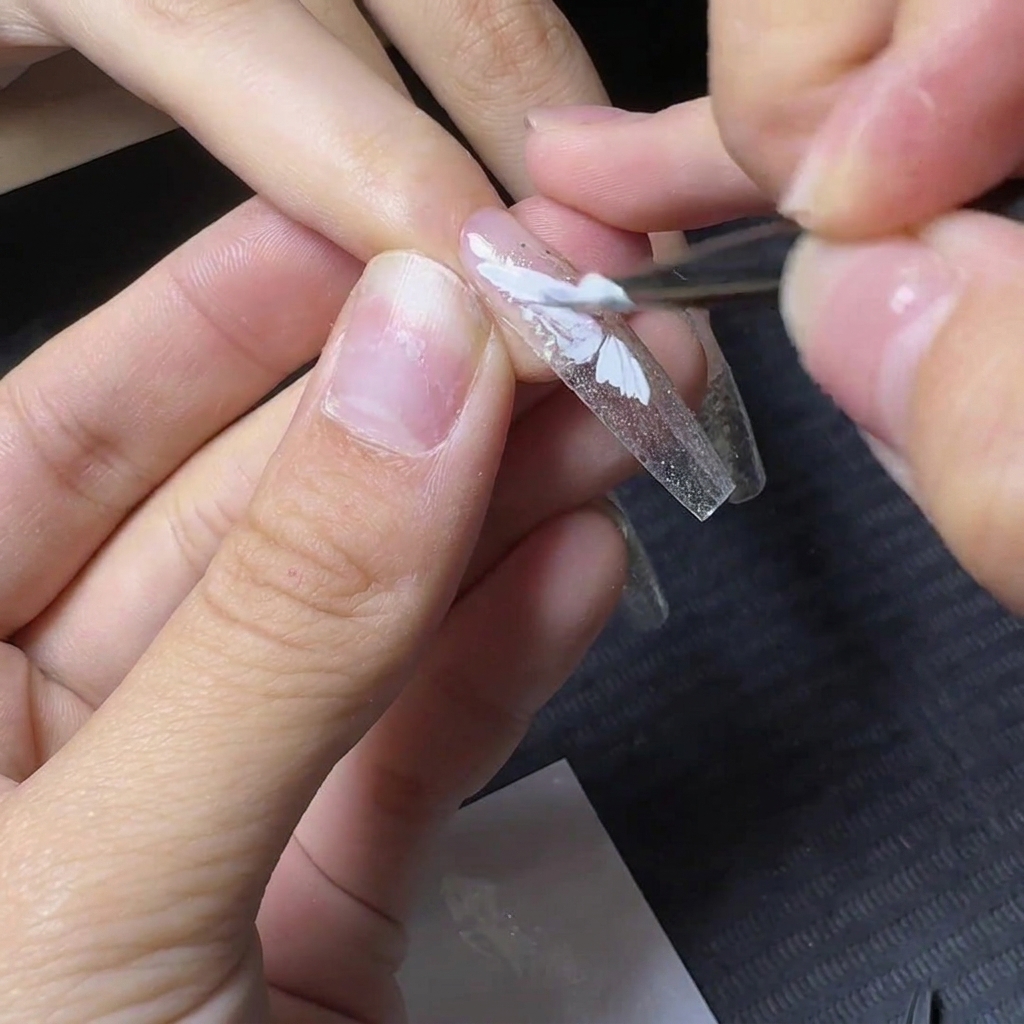 Un pincel de detalles rellenando la sección inferior del diseño de ala de mariposa en gel blanco.
