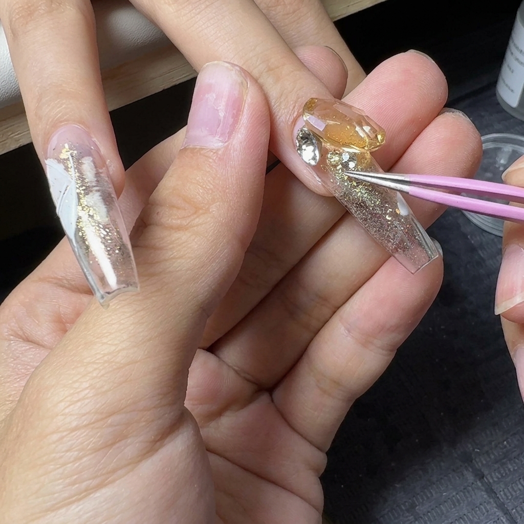 Pinzas de precisión colocando pequeños cristales alrededor de una gema central grande en una uña con purpurina.