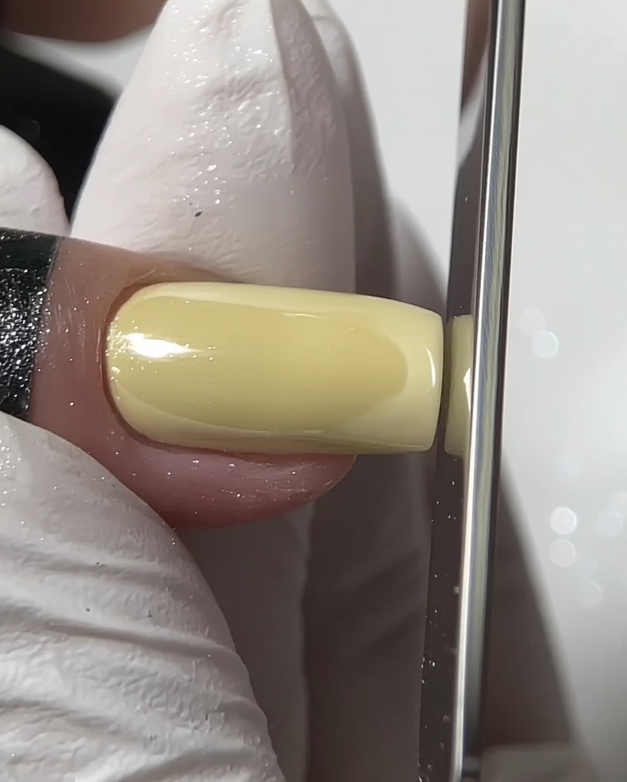Una lima de uñas dando forma al borde libre de una uña cuadrada con cromo.