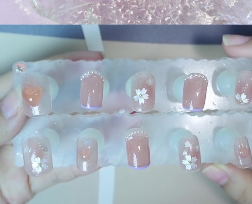 Vista en primer plano de una pequeña cuenta de acero colocada en el centro de un diseño de arte de uñas floral.