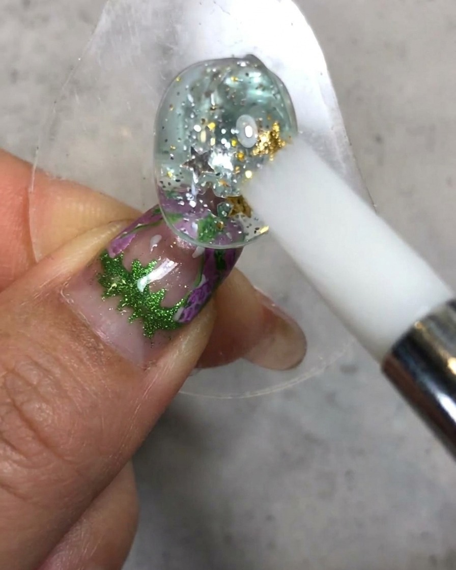 Un pincel de silicona blanco esculpiendo y alisando la textura de gel suave candy sobre la superficie de la uña decorada.
