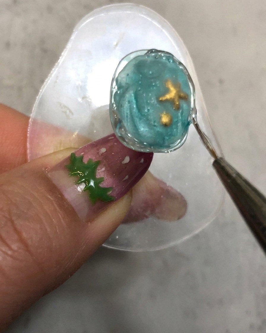 Un pincel de detalles trazando a lo largo del borde texturizado de gel de diseño curado de la uña.