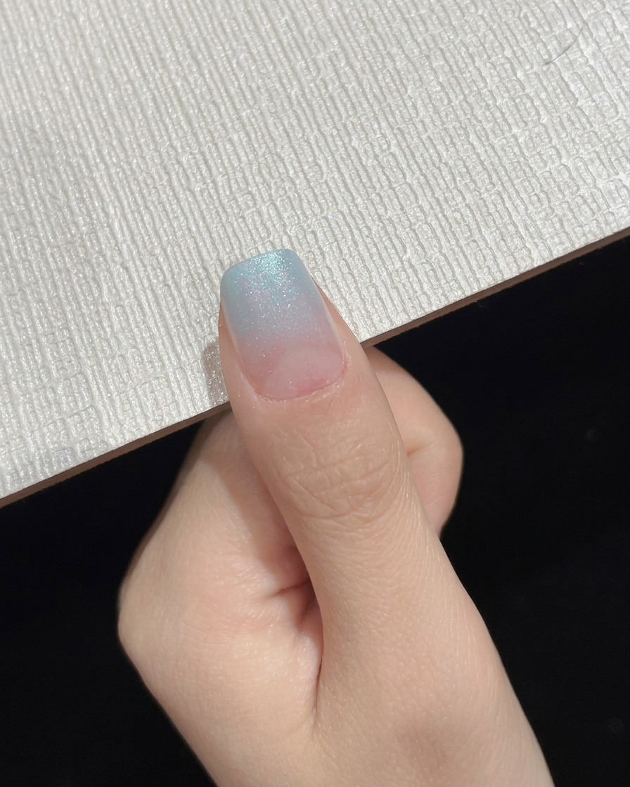 Una uña ombre con degradado azul terminada mostrada como toma de progreso intermedia.
