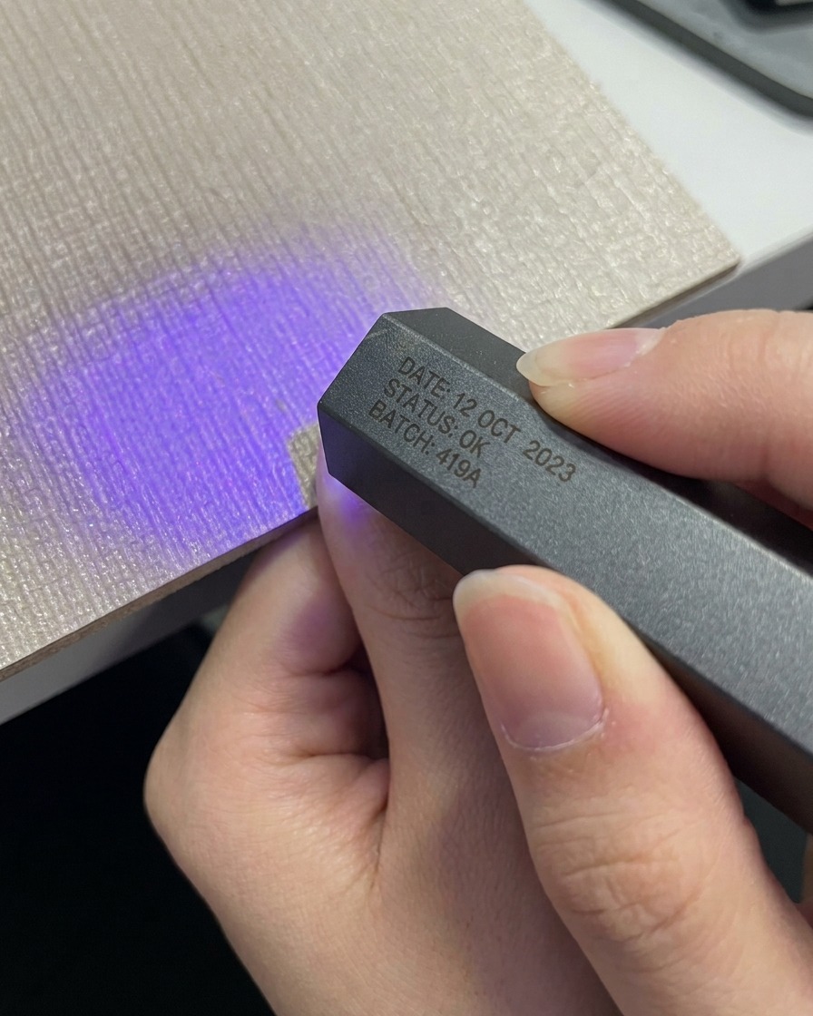 Una mano colocando un pulgar bajo una lámpara portátil compacta gris UV LED.