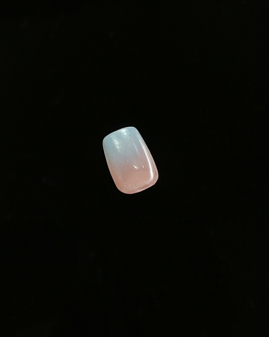 Un primer plano de una sola uña terminada que muestra un efecto ombre degradado contra un fondo oscuro.