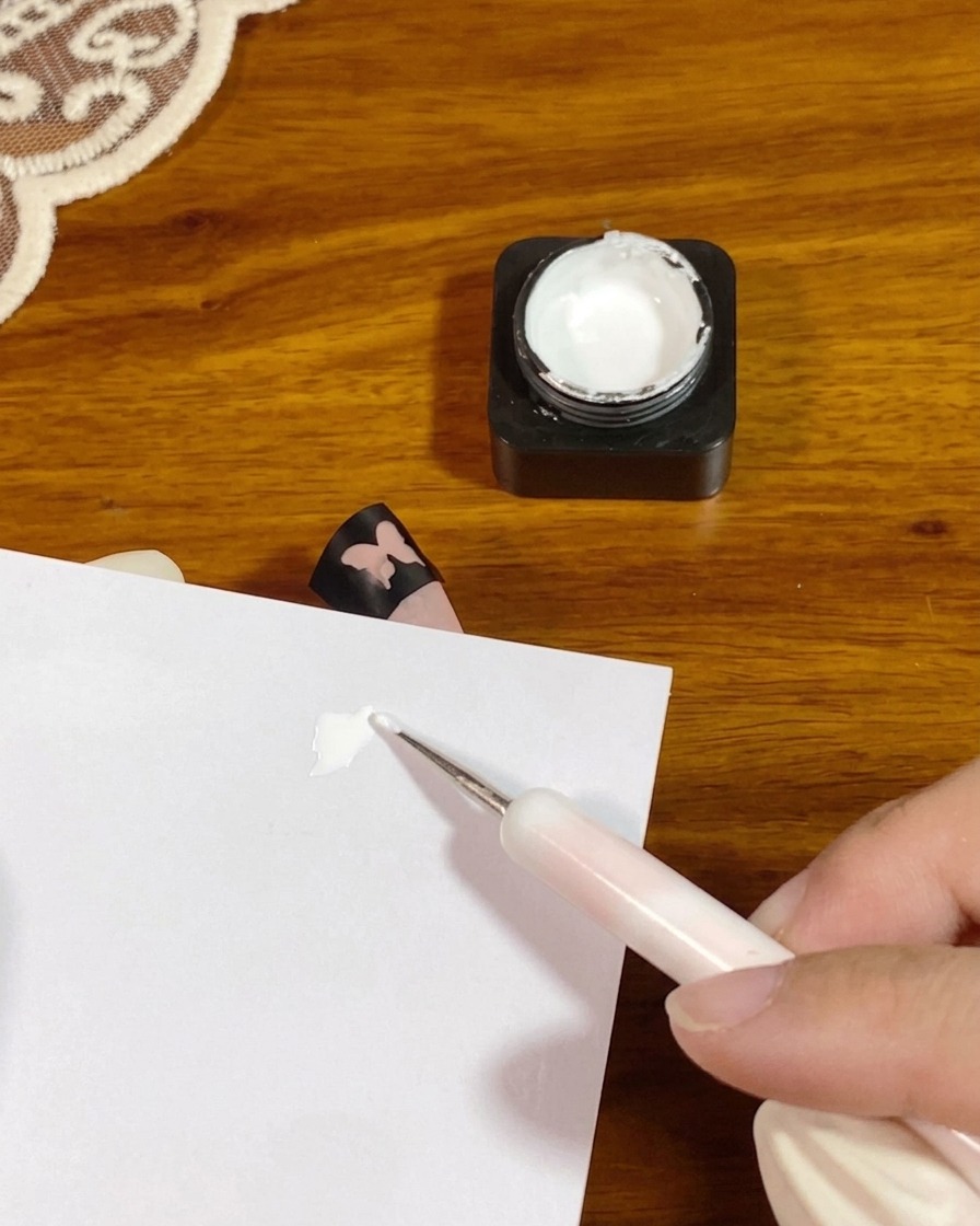 Una herramienta para hacer puntos colocando una pequeña porción de gel de toques blanco y espeso en una paleta de papel.