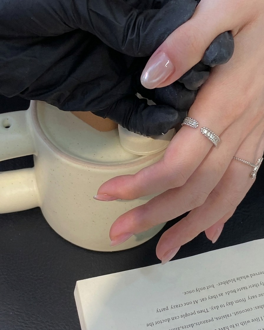 Un pincel aplicando una capa de top coat transparente sobre una manicura de ojo de gato terminada.