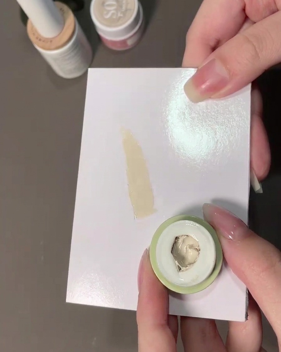 Una esponja tomando gel difuminador blanco lechoso de una paleta.