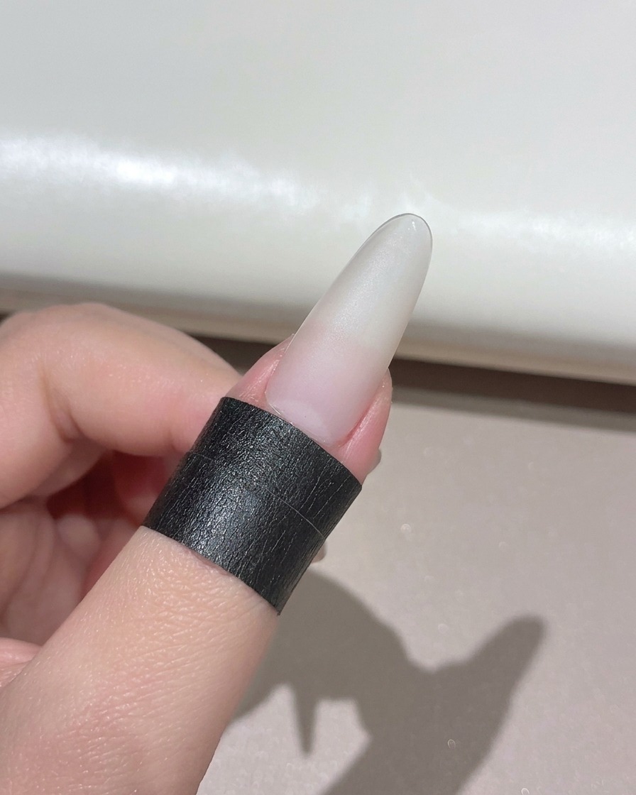Una uña con manicura colocada debajo de una lámpara UV LED portátil compacta.