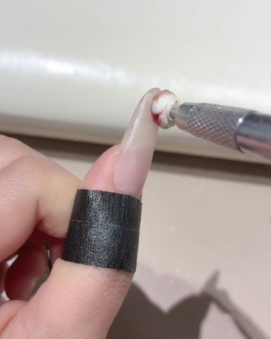 Una pequeña herramienta de esponja aplicando gel mixto en la punta de una uña manicurada.