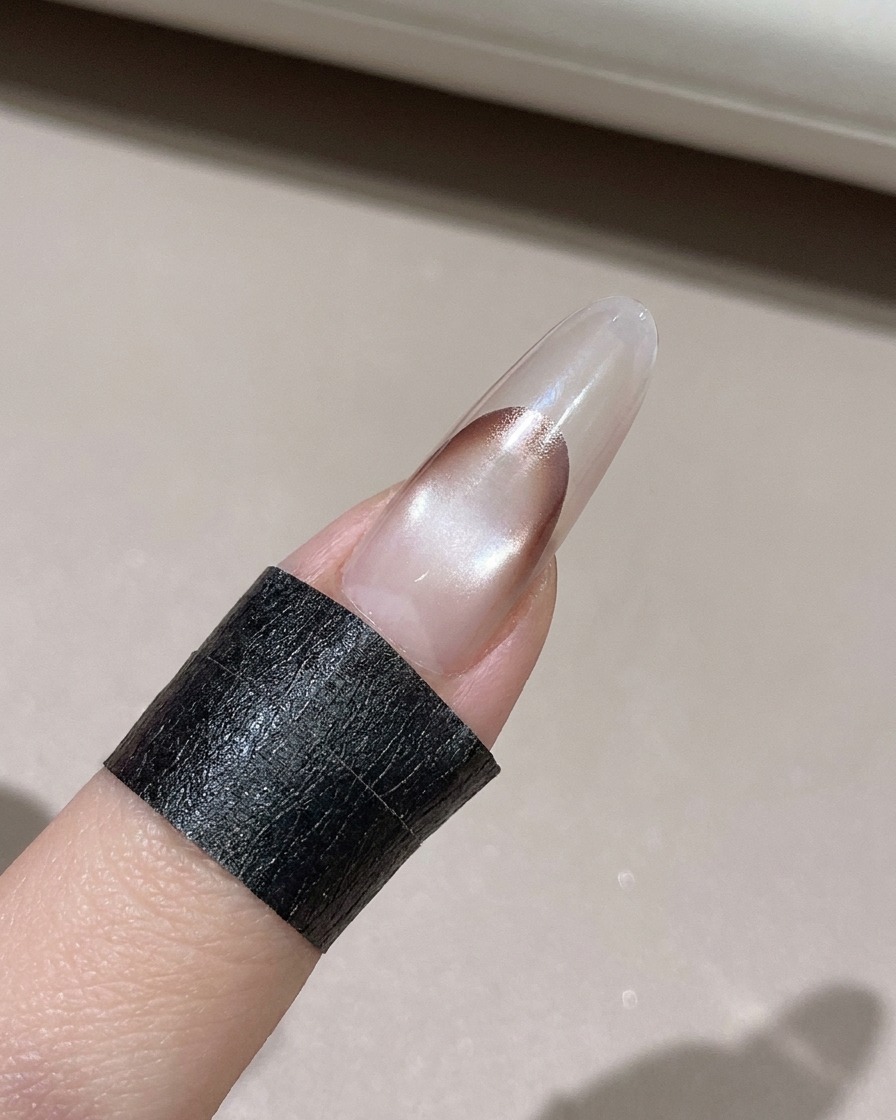 Una toallita sin pelusa limpiando el exceso de gel del borde de una uña decorada.
