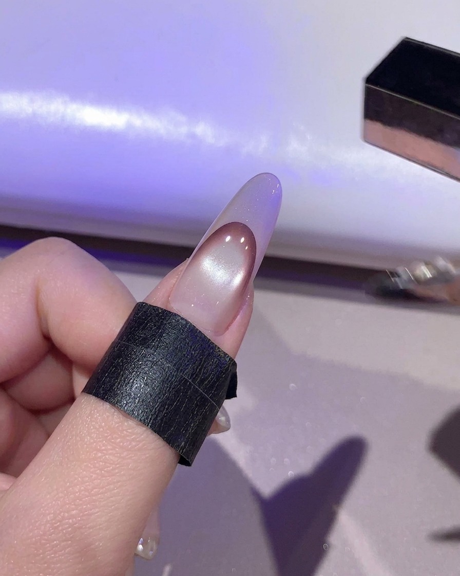 Una uña curándose bajo luz púrpura dentro de una lámpara UV/LED.