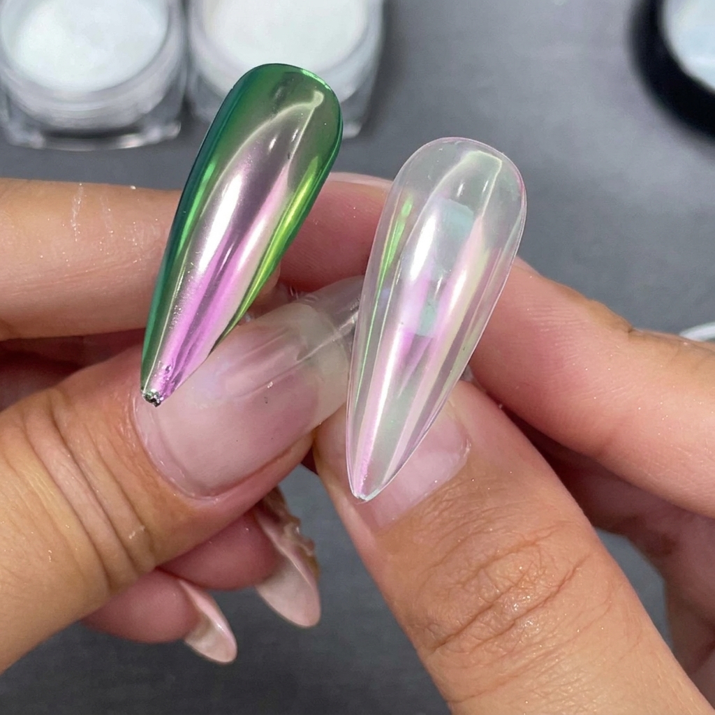 Dos puntas de uñas stiletto terminadas sostenidas lado a lado, una con base transparente y otra con base negra que muestra un cambio verde-púrpura.