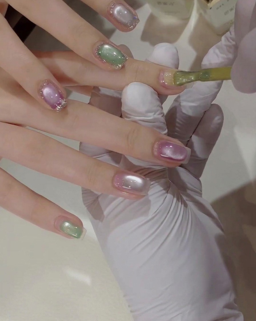 Un primer plano detallado de un pincel de uñas aplicando esmalte de gel amarillo brillante sobre una uña natural.