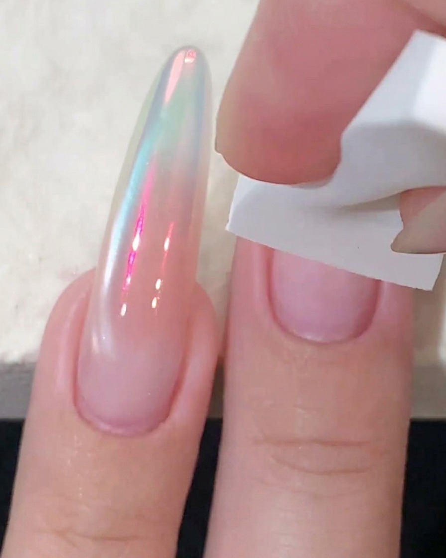 Una esponja blanca dando toques de gel rosa blush en el centro de una uña para intensificar el color.