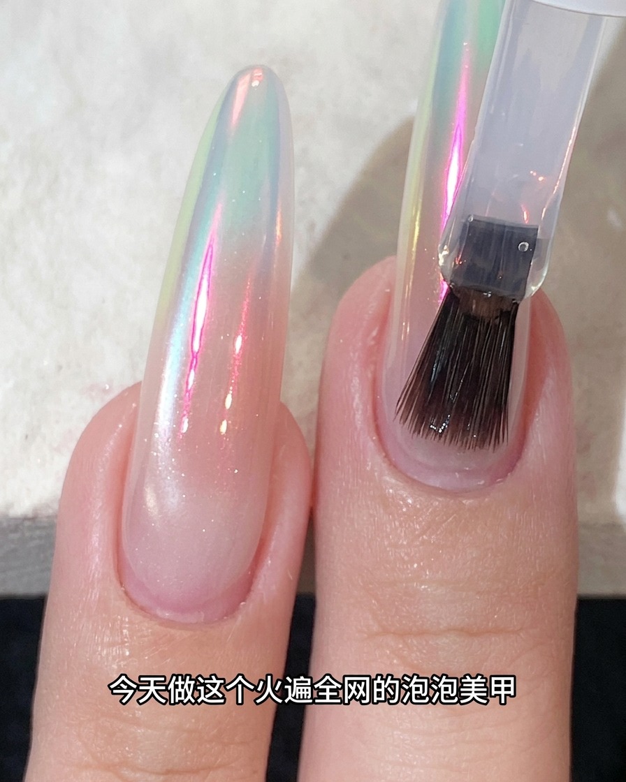 Un pincel aplicando top coat sobre una uña brillante con acabado cromado.