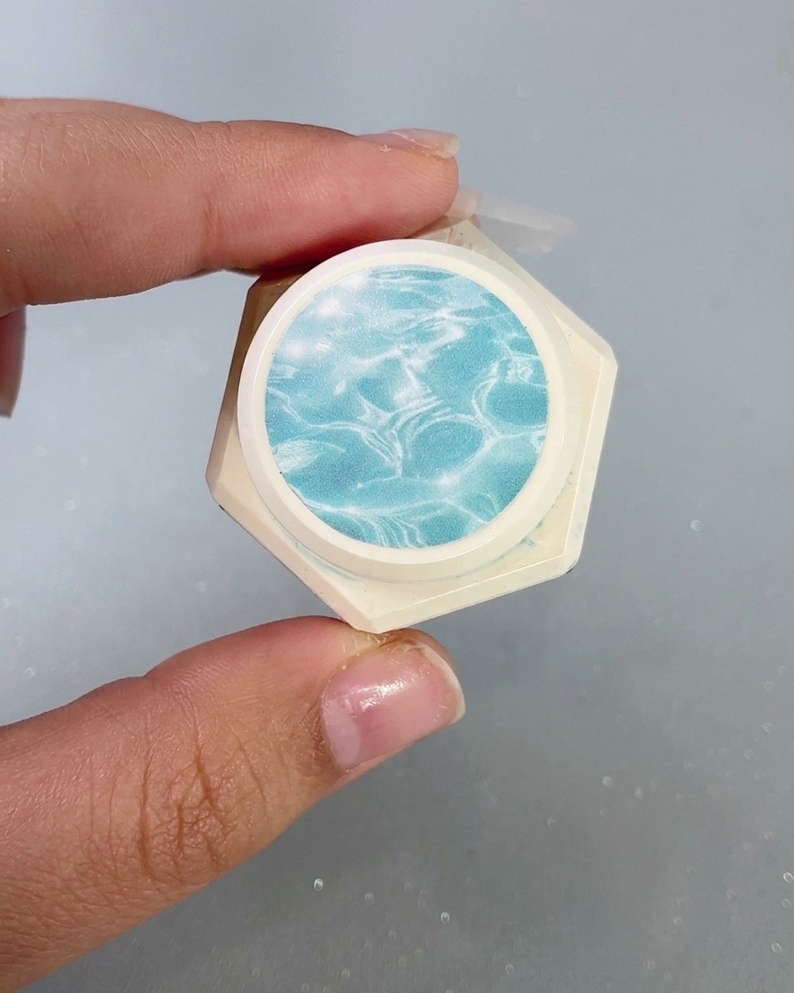 Un recipiente que muestra gel efecto vidrio de alta transparencia con un patrón de ondas de agua en la etiqueta.