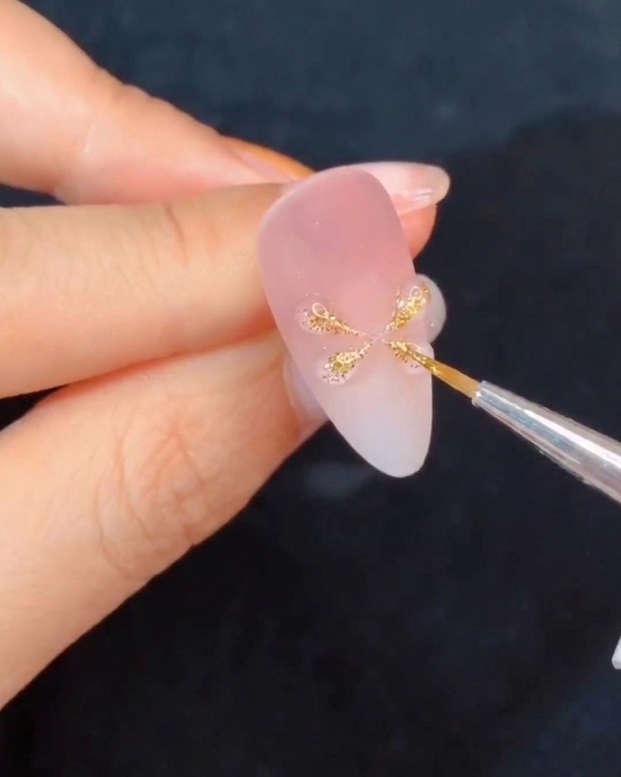 Una mano sosteniendo una uña bajo una lámpara de curado, resaltando los detalles de gel recién formados.
